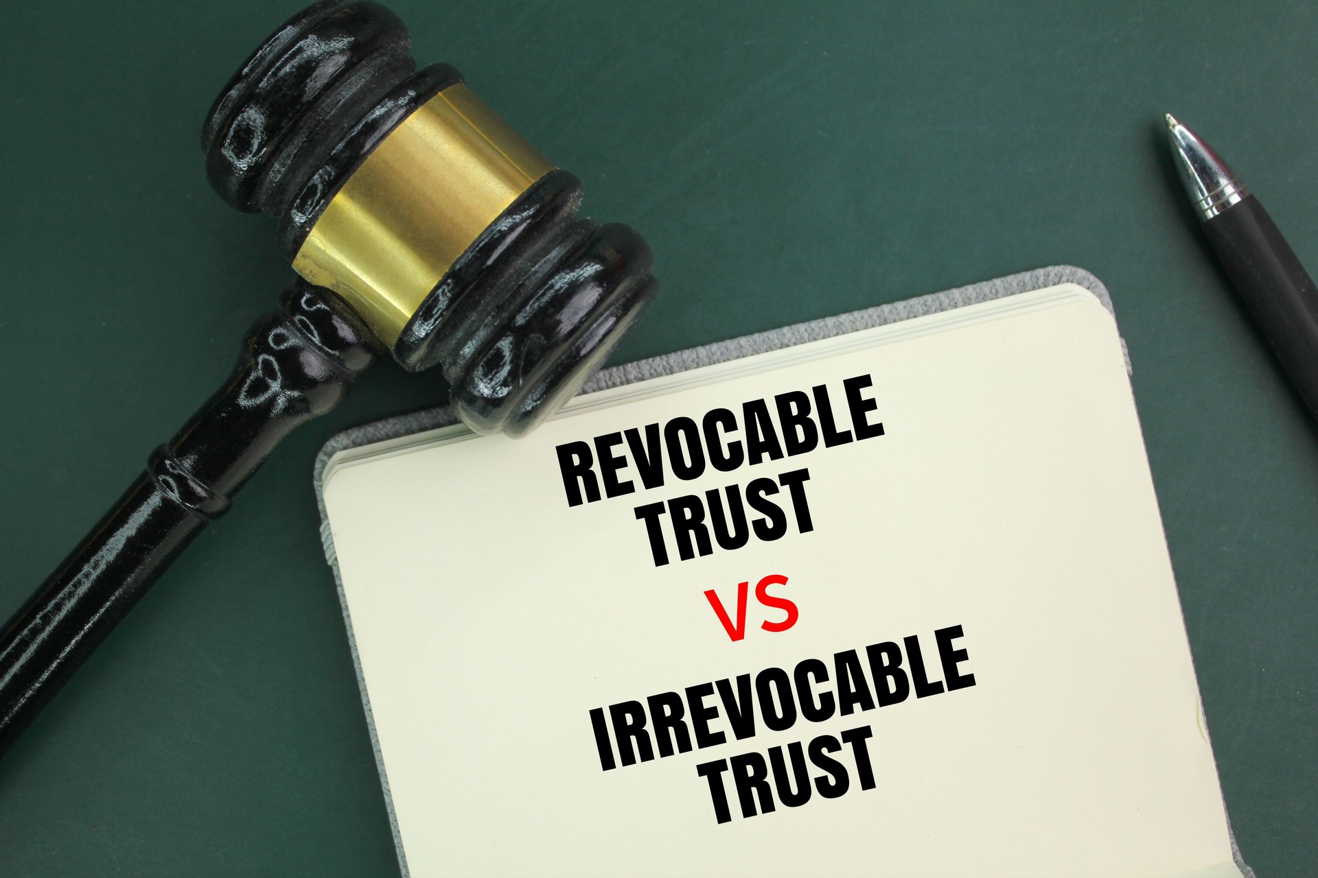 Judge's hammer, pen and book with the words Irrevocable Trust vs Revocable Trust